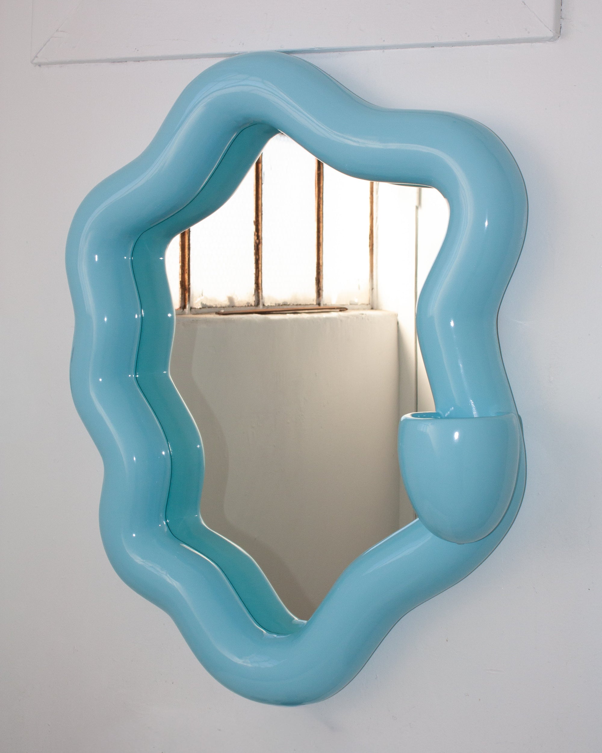 Blue wavy mirror on a white wall